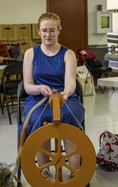 Young spinner in blue dress tries her hand at the new technique.