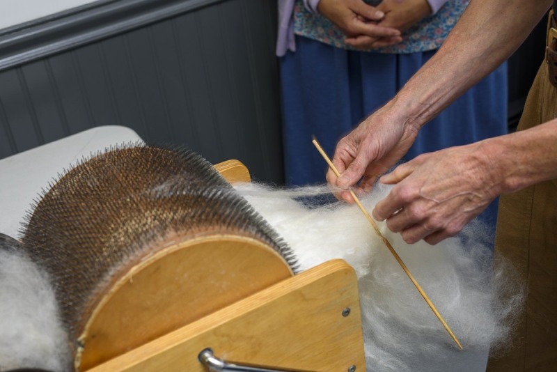 Christina used a fine wooden chopstick to lift fleece from the carder.