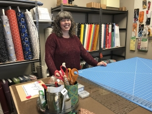 Melly at Makers' Way Studio surrounded by fabrics on the bolt.