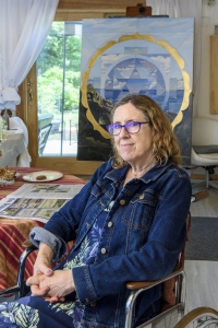 Nancy Grice seated before one of her paintings