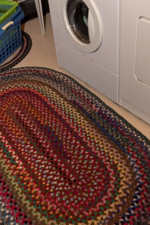 A lovely colored rug in front of the washer/dryer units.